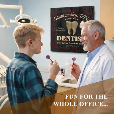 Older dentist in a dental office playing darts with a younger person in front of a personalized dentist dartboard cabinet.